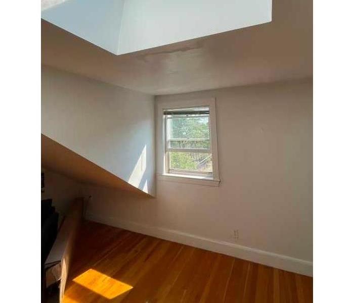 A leaky skylight during daytime with wet floorboards and ceiling drywall 
