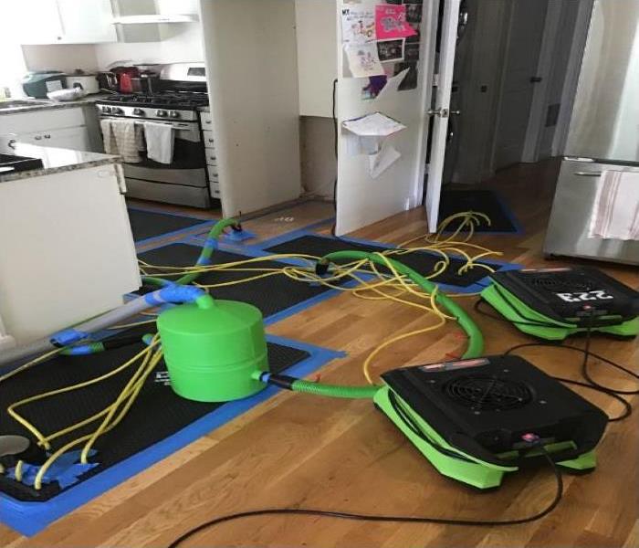 floor mat and green SERVPRO fans drying hardwood floor